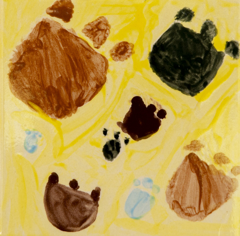 Painting of several brown and black paw prints scattered across a yellow background.