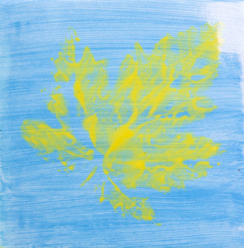 Painting of a leaf print in yellow, against a blue background.