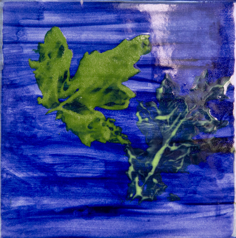 Painting of leaf print showing two green leafy shapes on a dark blue painted background.