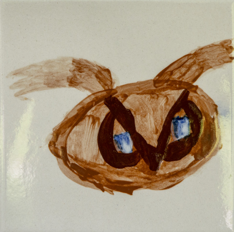 Painting of an owl head with a round brown face, large blue eyes outlined in dark paint, and simple wing shapes on the sides.